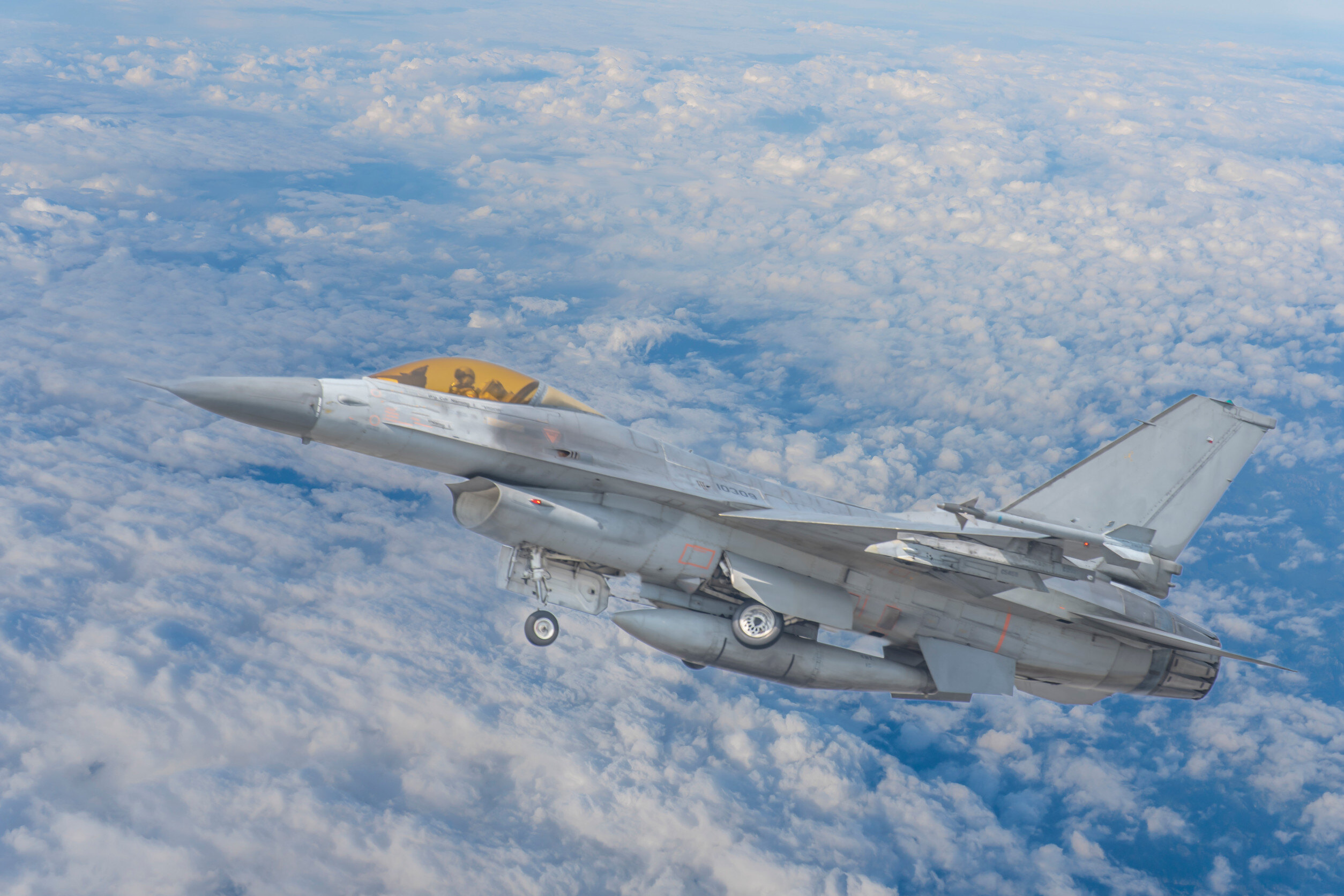 military fight jet flying above the clouds