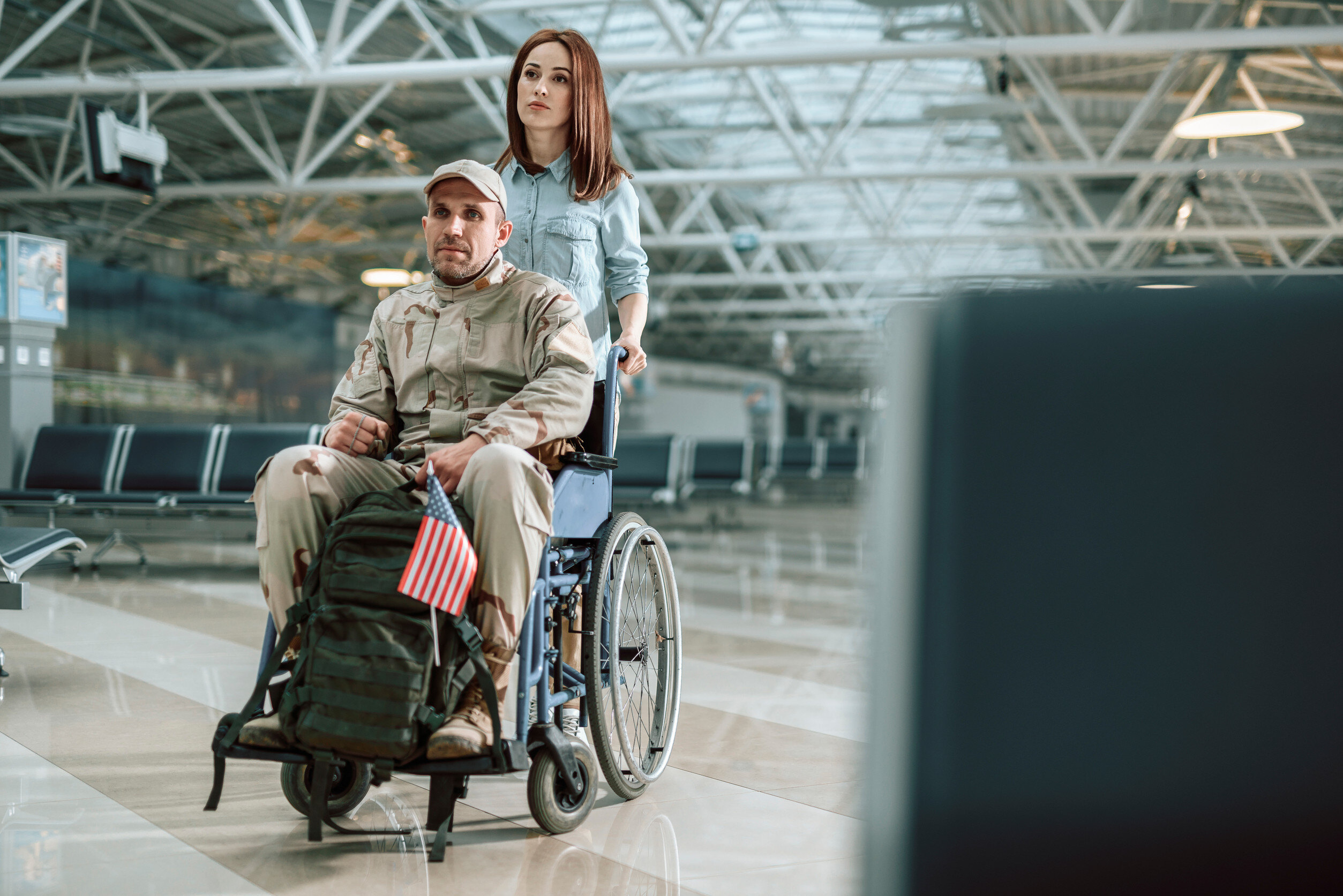 a woman pushes a uniformed veteran in a wheelchair