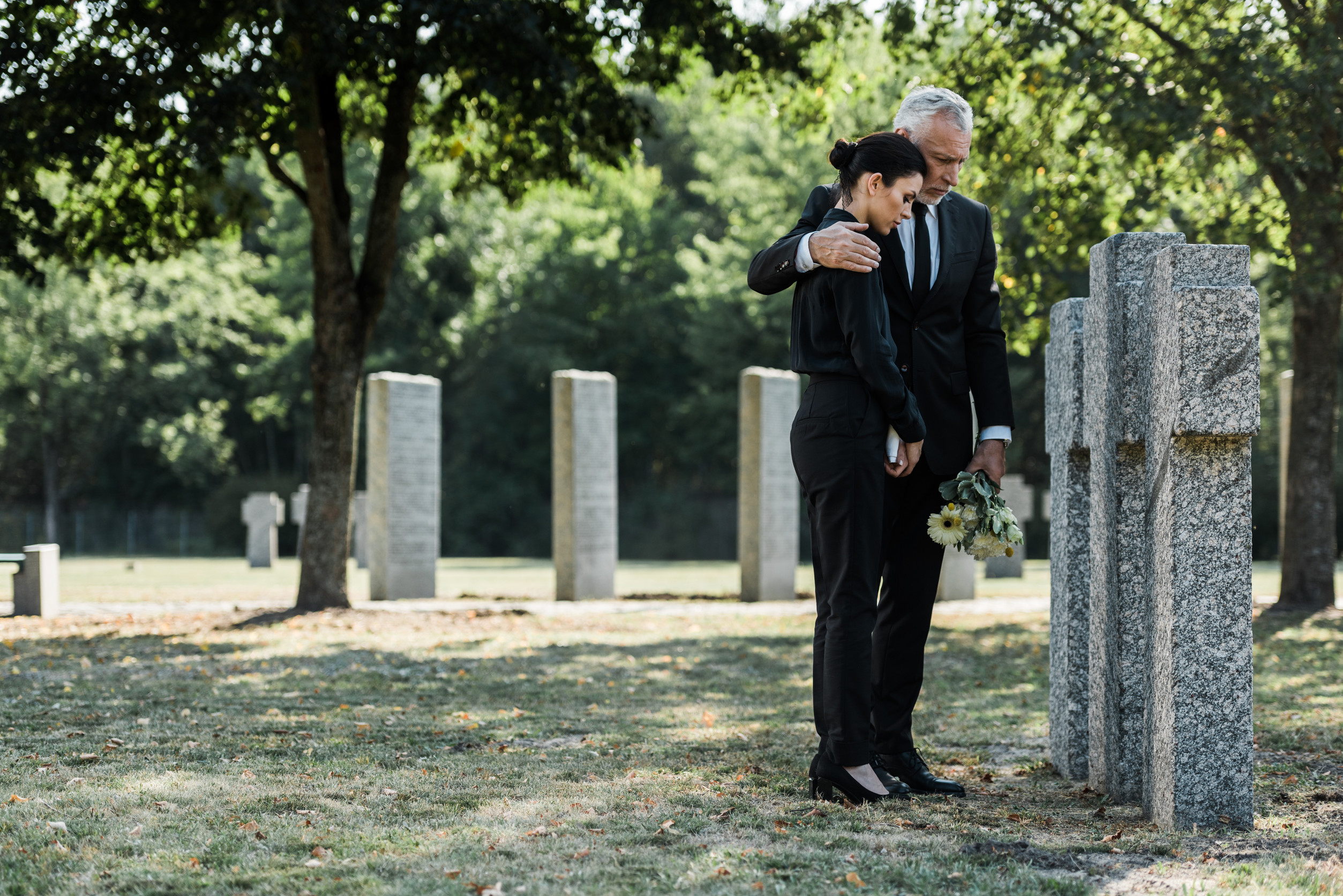 a man and a woman dressed in black pay their respects in a cemetery