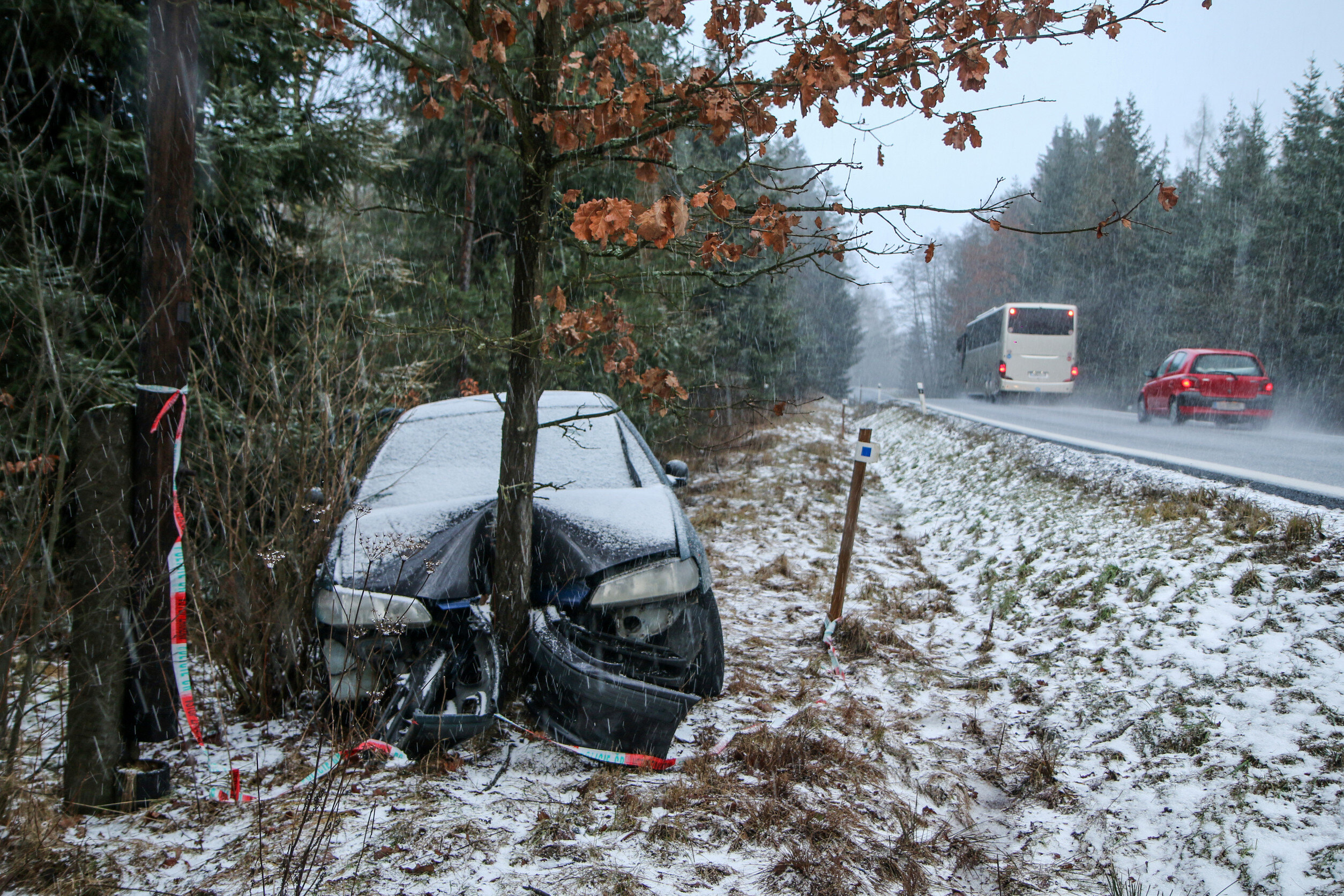 a car that has crashed into a tree next to a snowy road