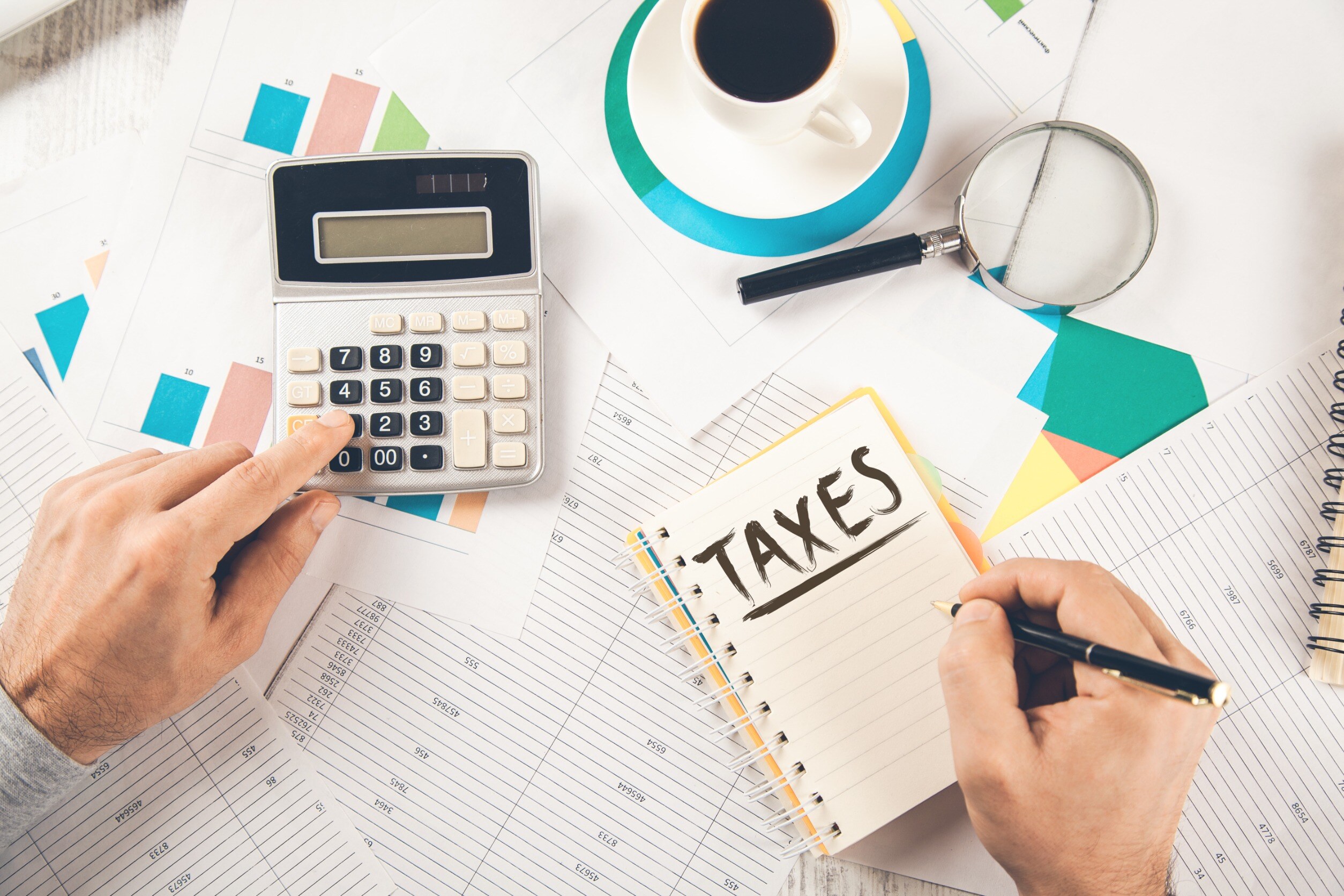 person doing taxes at desk with notebook and calculator