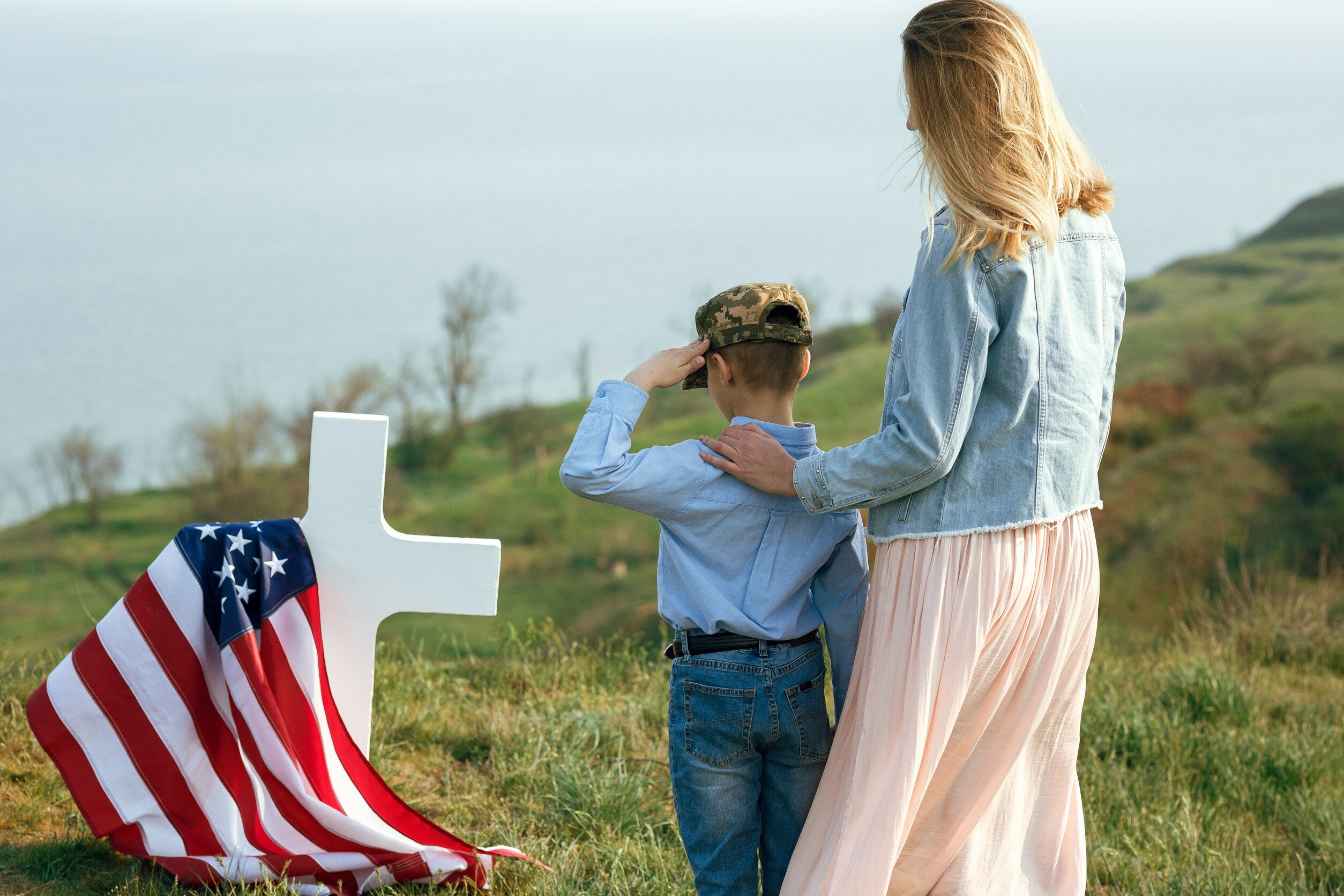 a mother and her child visit the grave of a veteran family member draped with an American flag