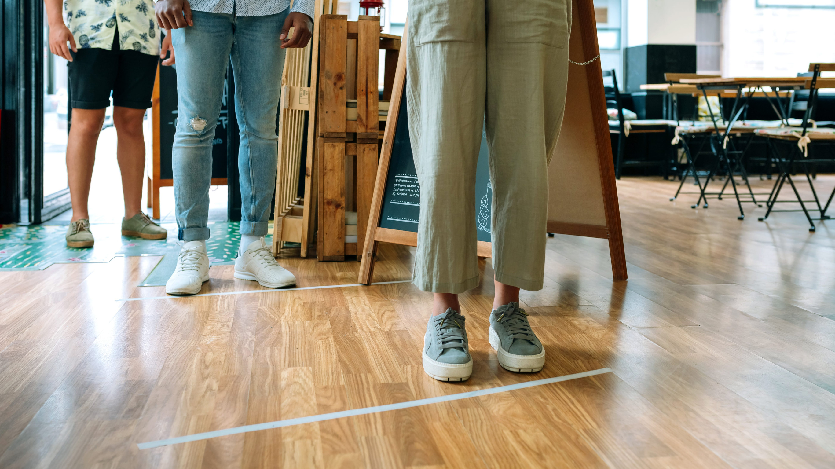 waist down shot of people social distancing while standing in line to enter a restaurant