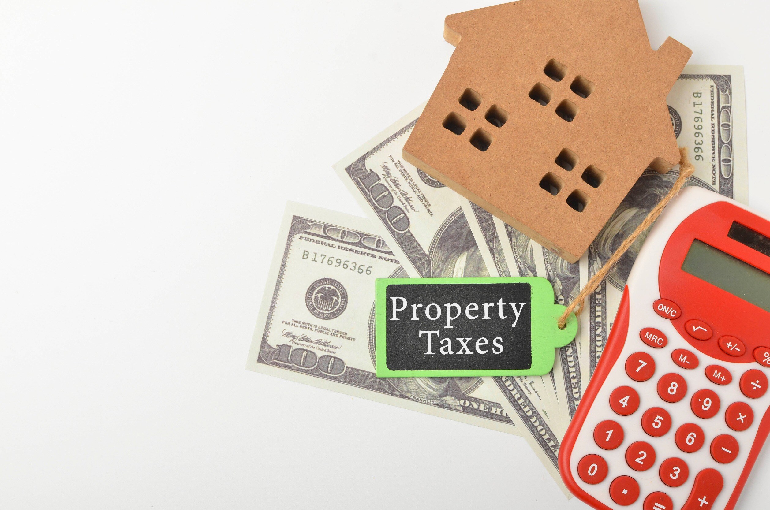On a white background, a model of a house, a calculator and dollars