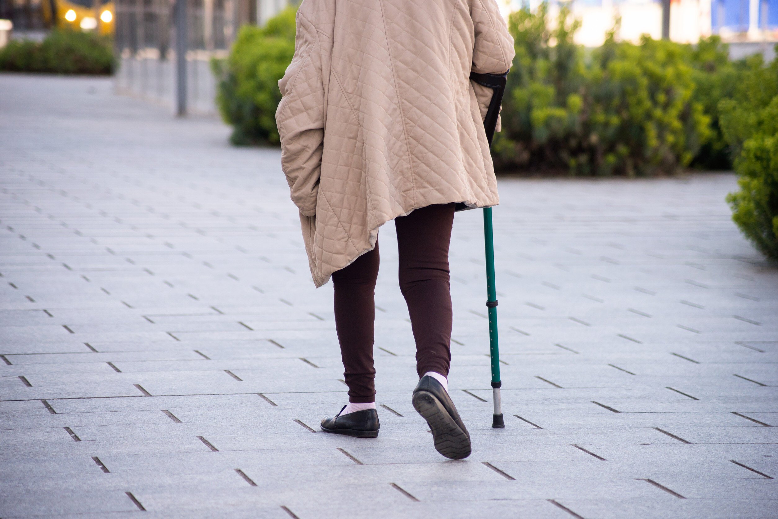 person walking with a cane on a stone walkway