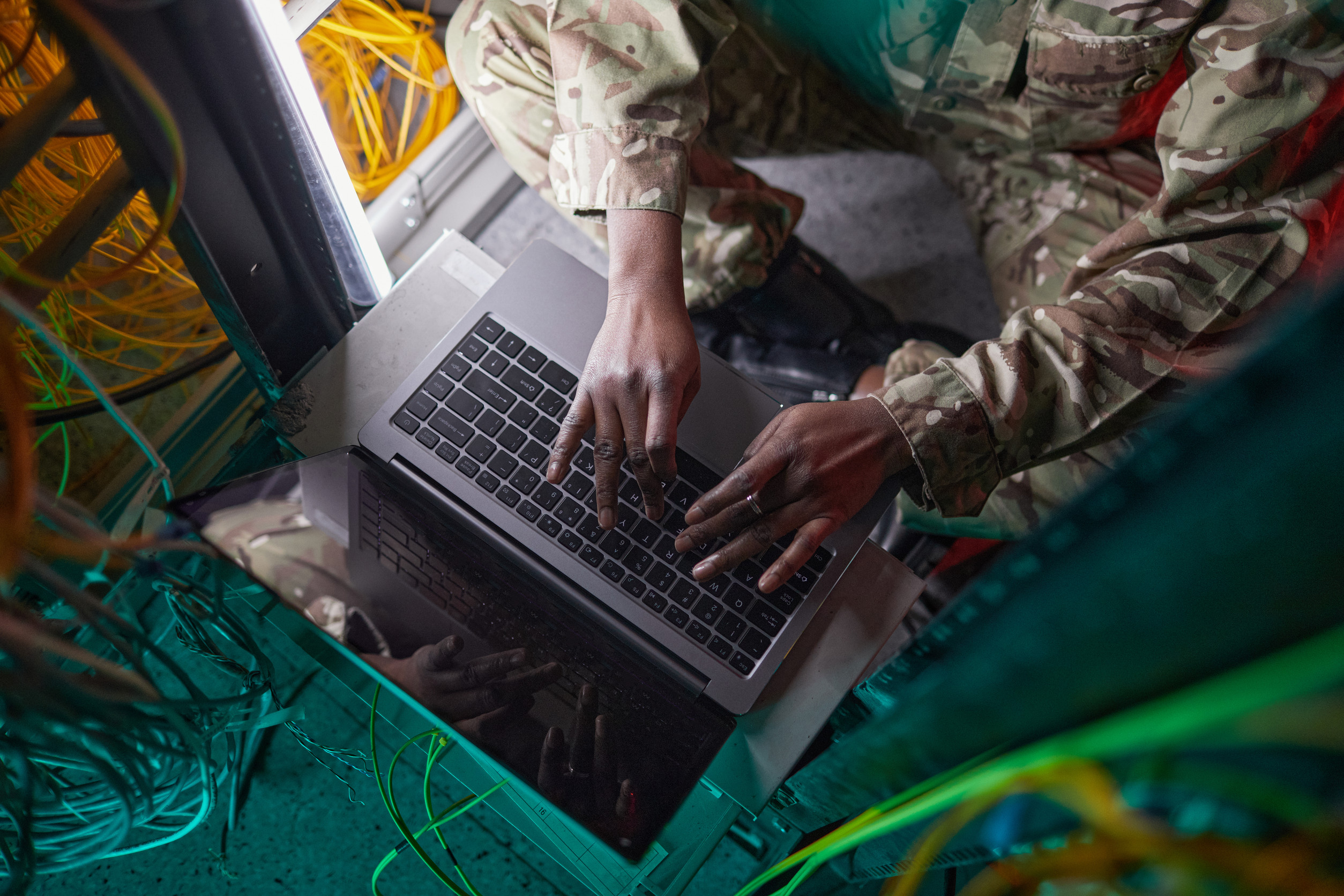 Cropped high angle portrait of young woman wearing military uniform while using computer in server room