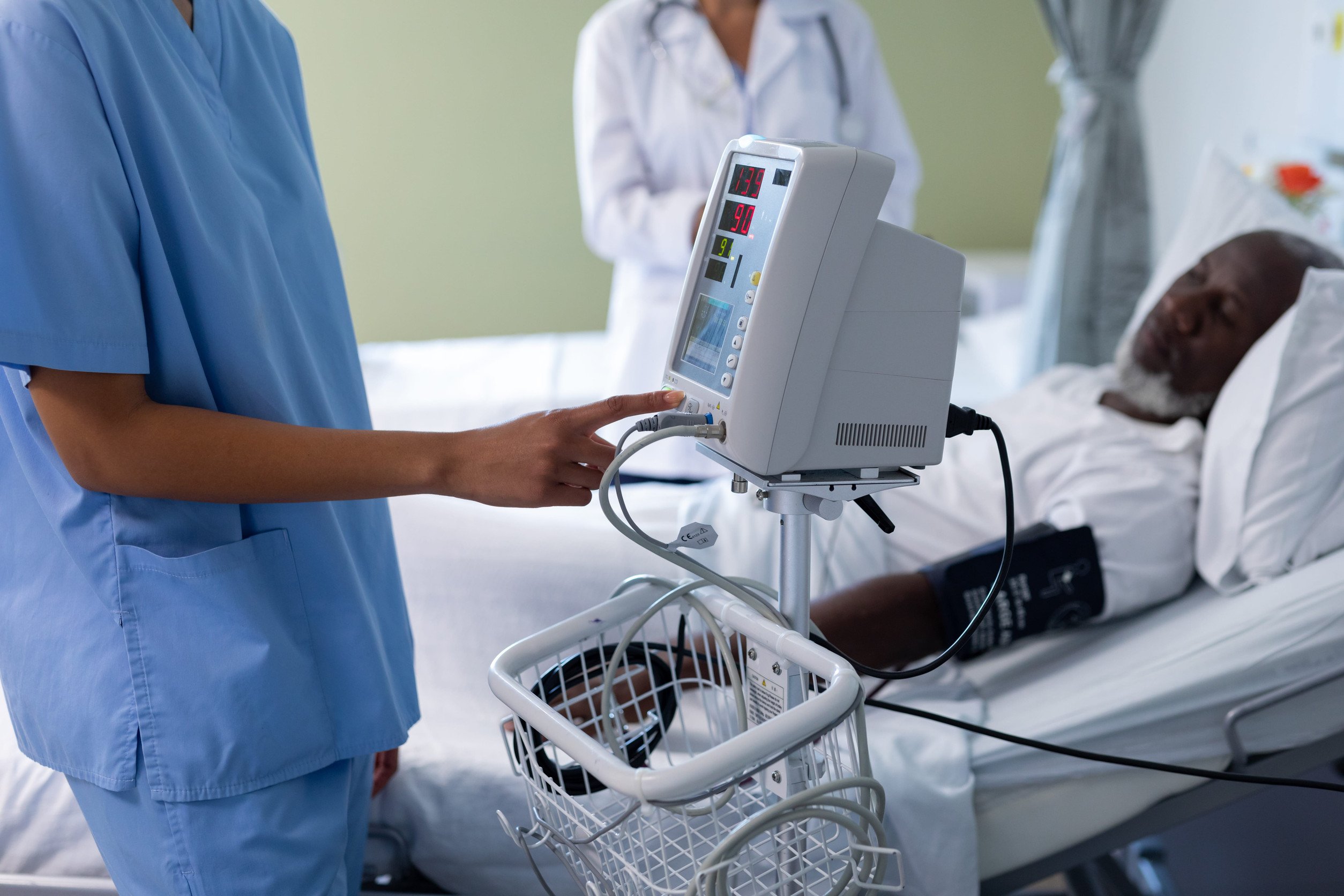 two medical professionals attend to a patient in a hospital bed