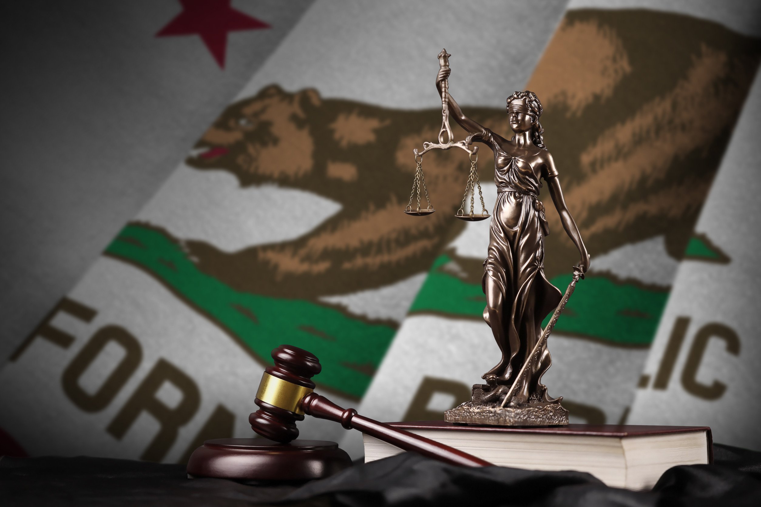 California US state flag with statue of lady justice, constitution and judge hammer on black drapery. Concept of judgement and punishment