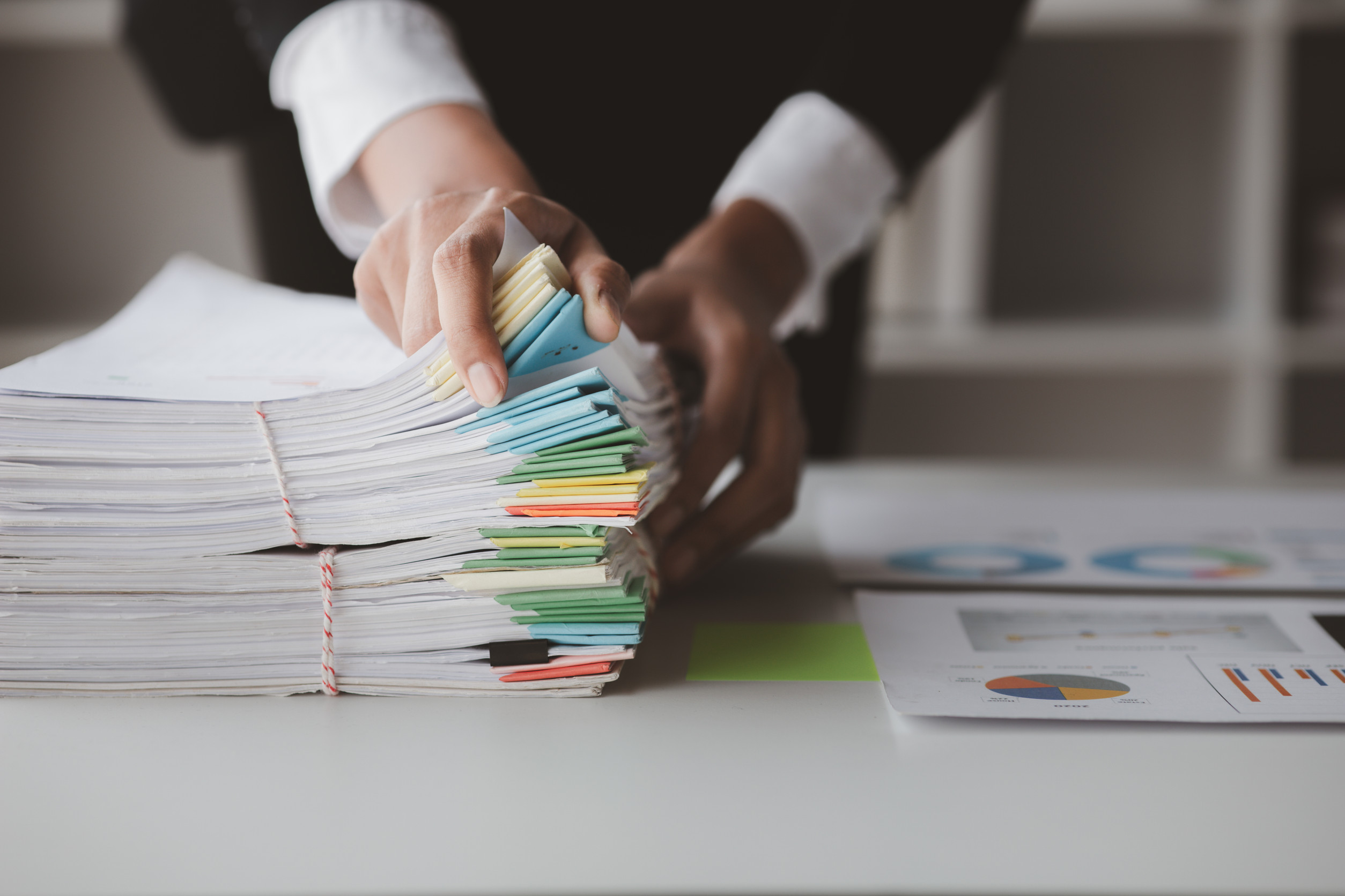 a person in professional business atire sorts through a stack of documents