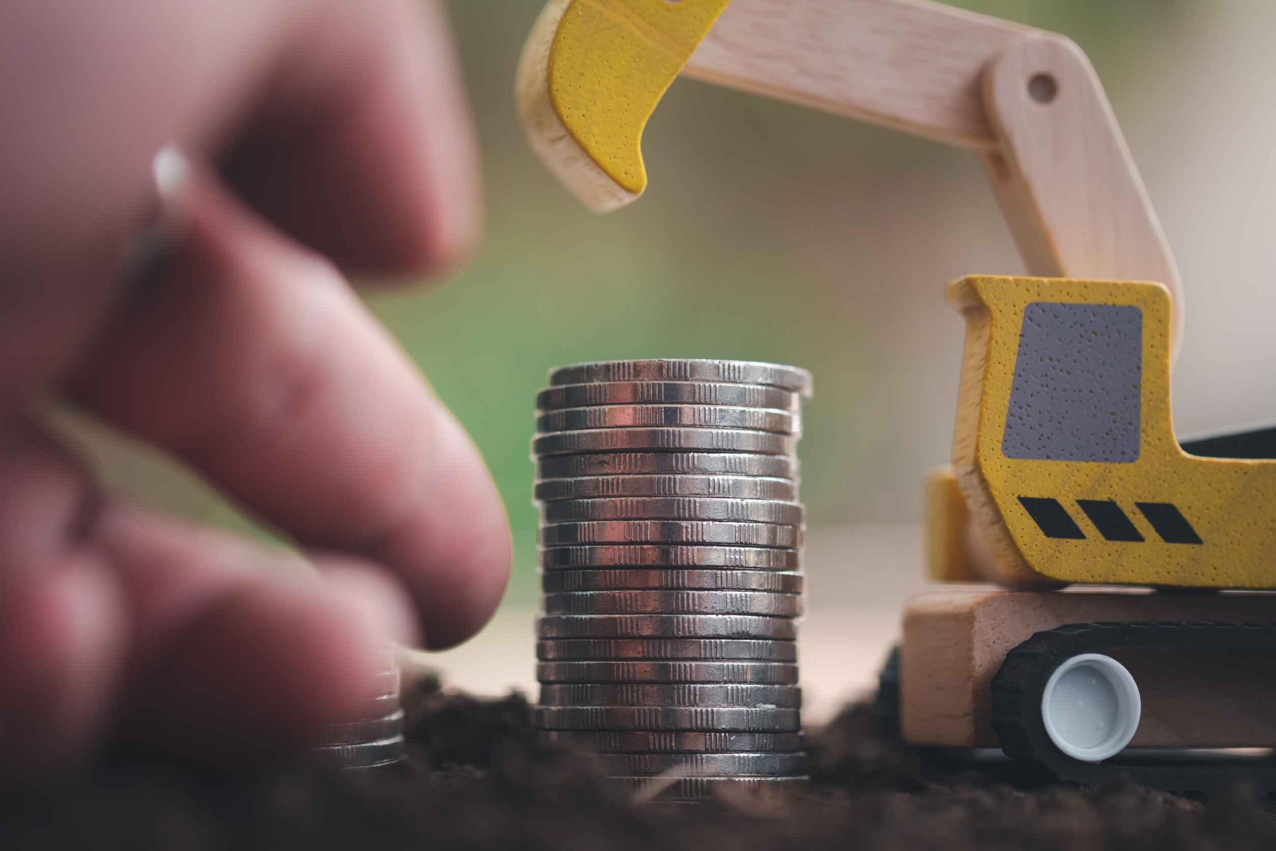 a small toy construction vehicle poised over a stack of coins