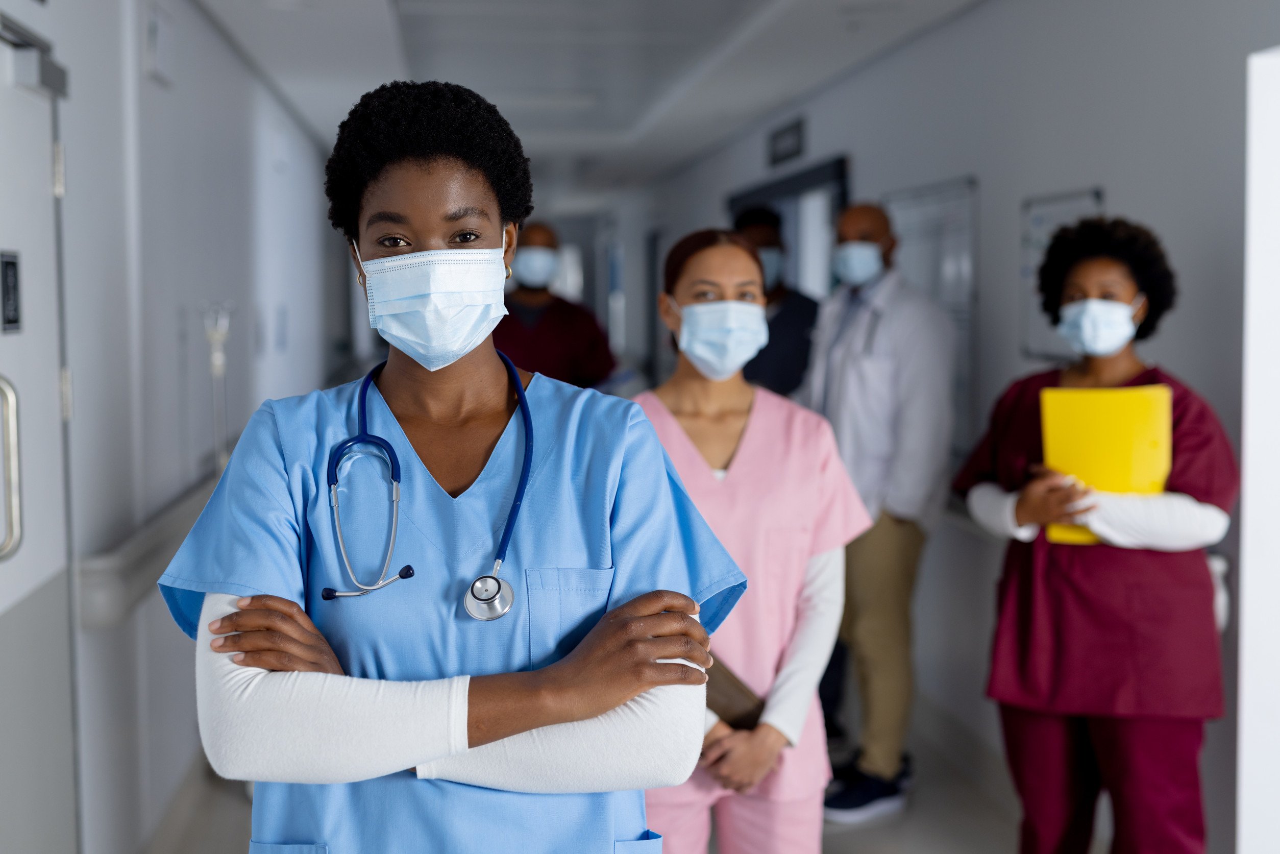 healthcare workers in scrubs and face masks stand in a hospital hallway