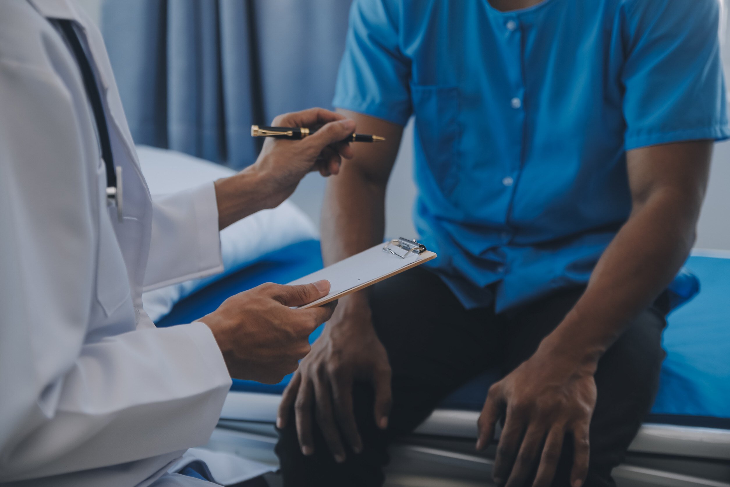 a doctor in a white coat examines a man sitting on a bed in a clinical setting