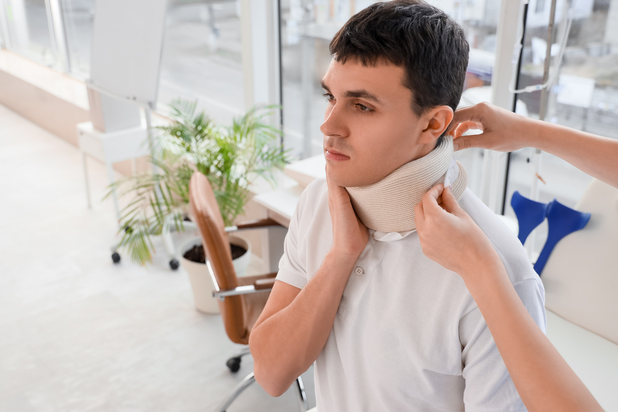 A young man receives care as a supportive hand secures a neck brace