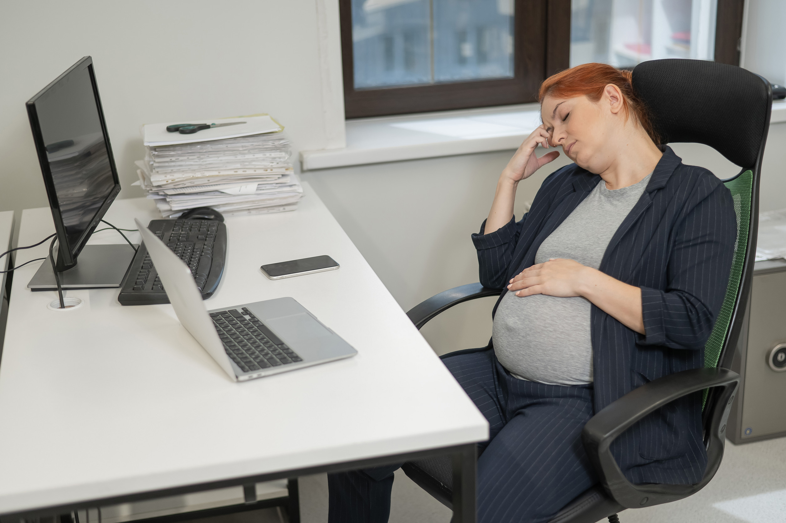 a pregnant woman sitting at her desk at work