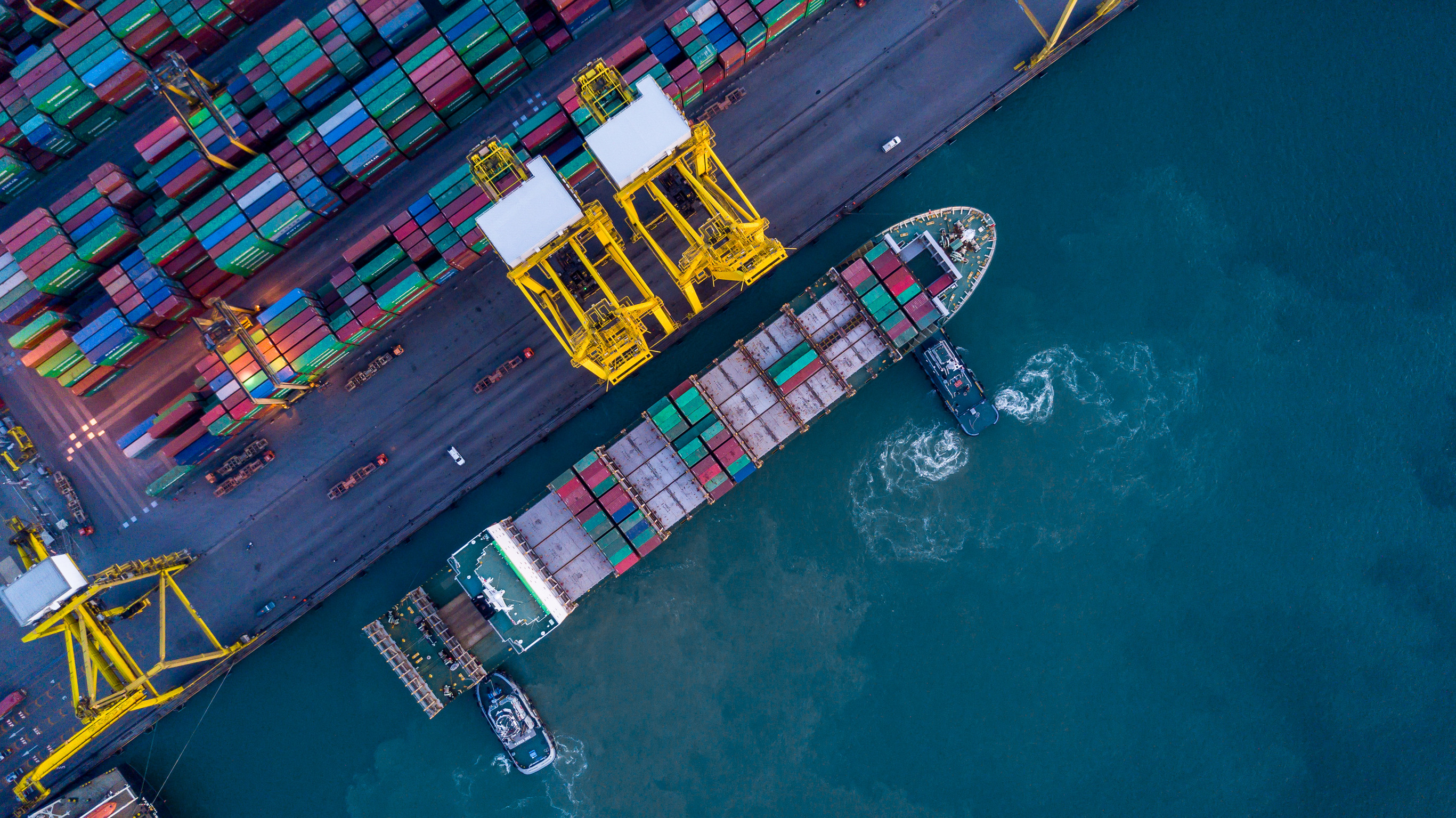 a cargo ship loaded with shipping containers docking at a busy port