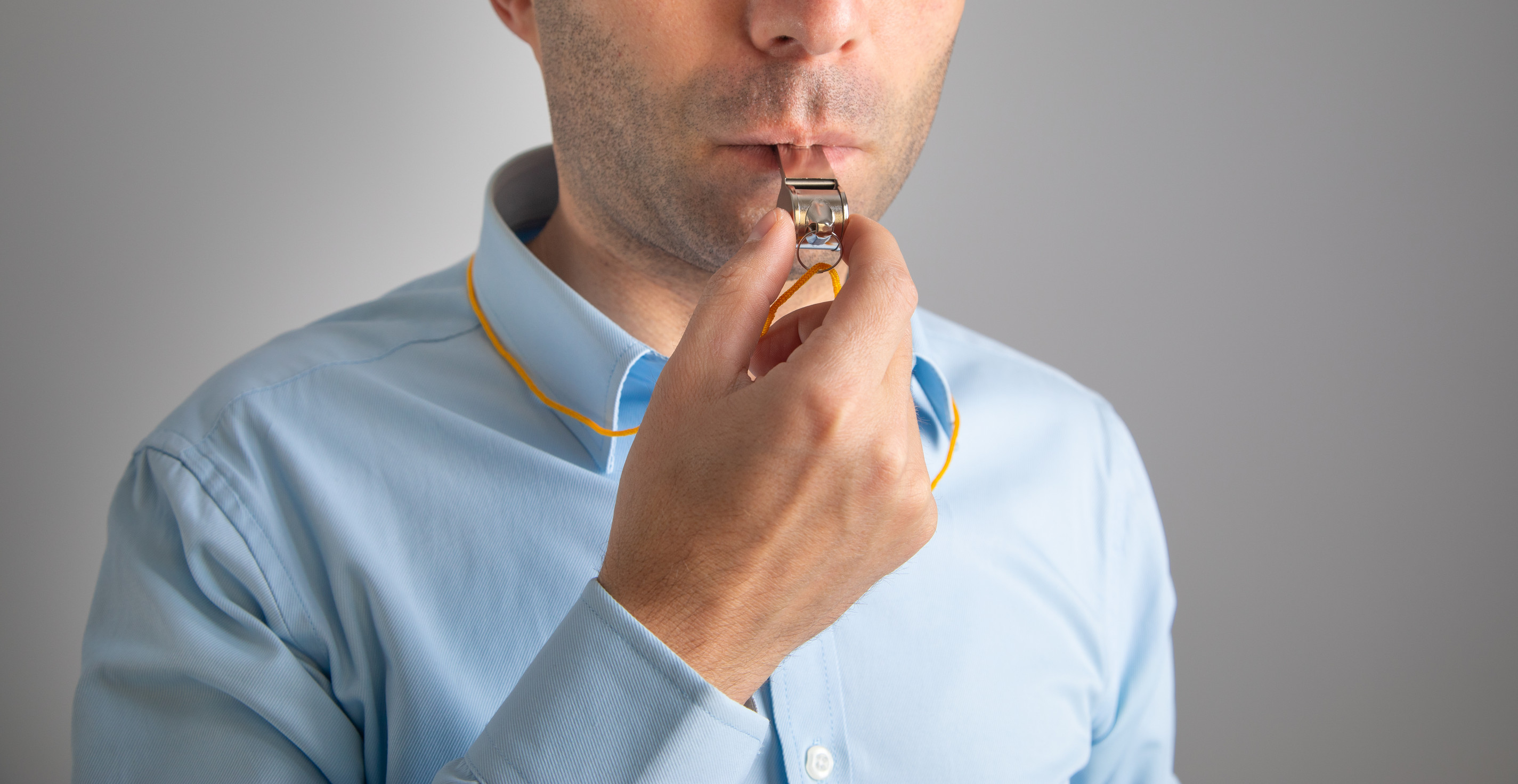 a man holds a metal whistle to his mouth