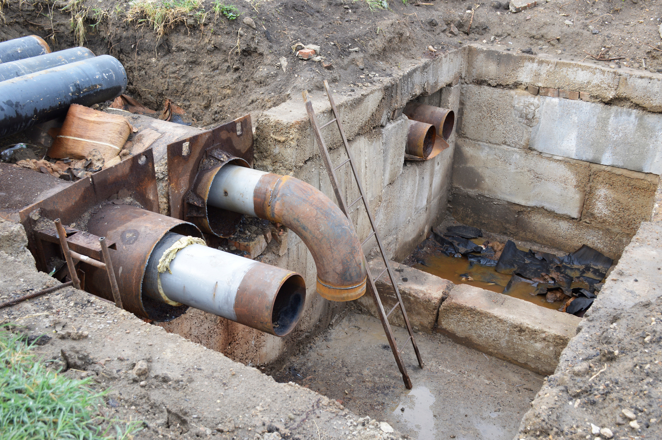 exposed underground pipes in a concrete pit at a contruction site