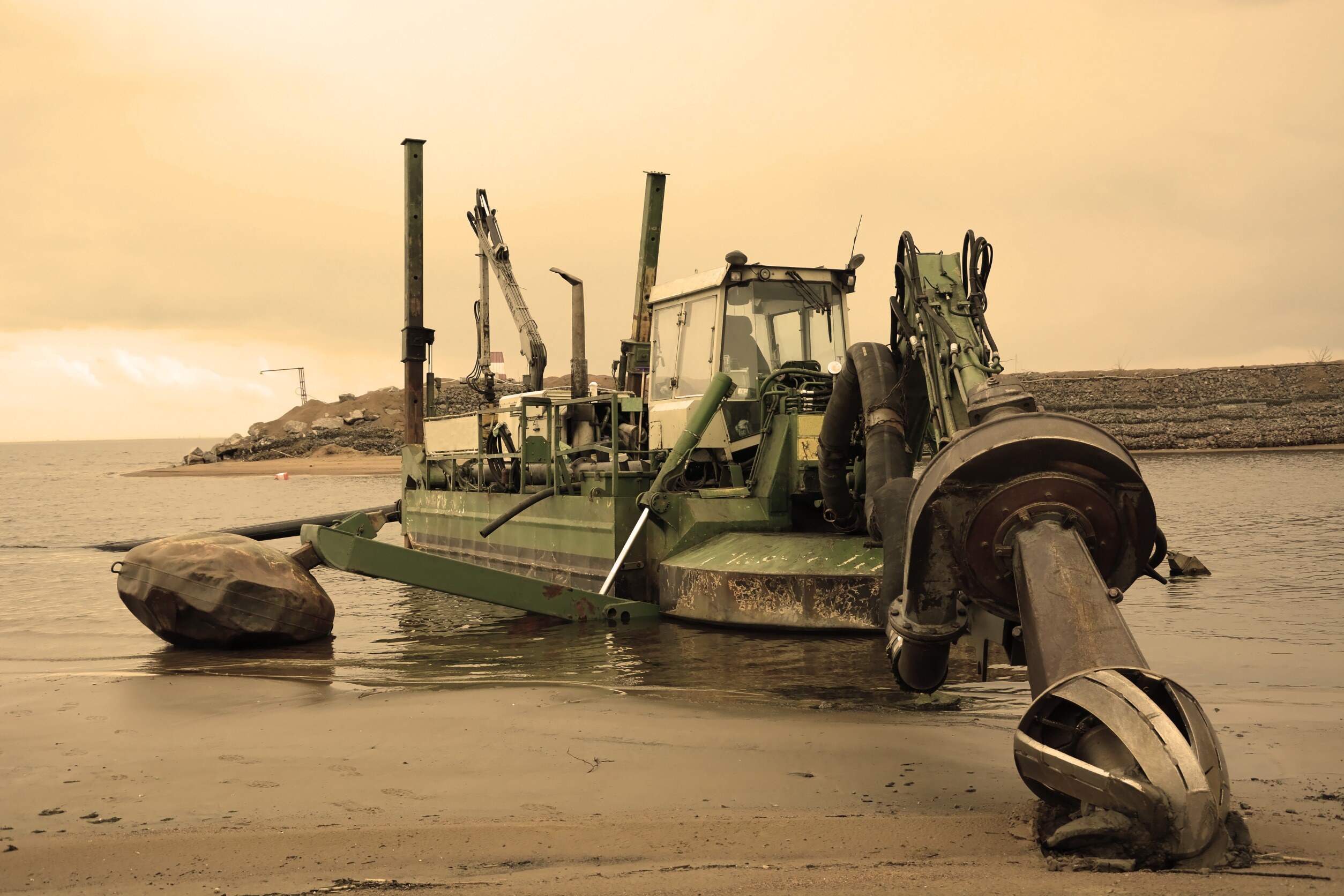 industrial ship on a beach with its drill planted into the sand