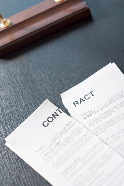 A contract torn in half resting on a black desk