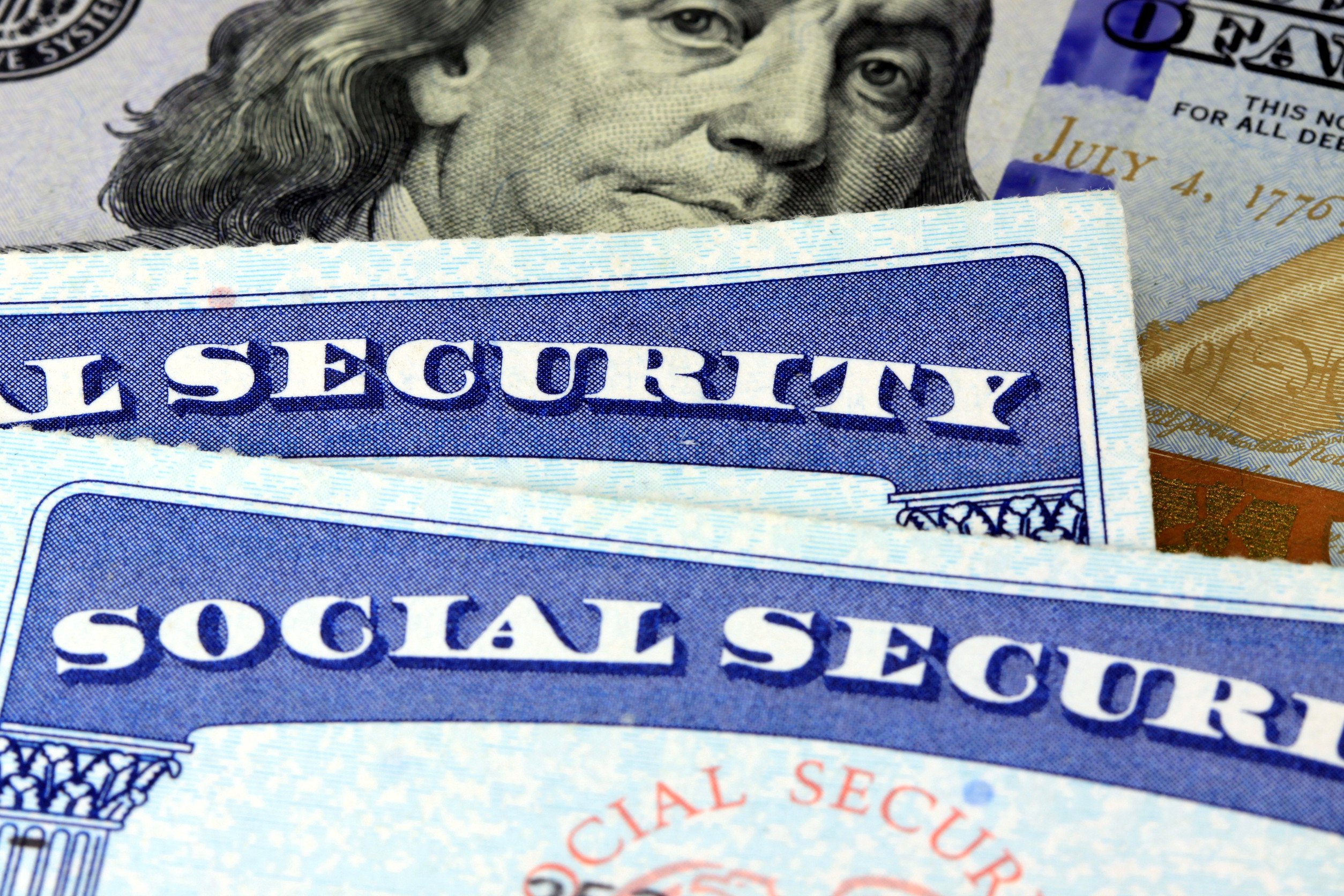 close shot of two social seccurity cards atop a hundred dollar bill