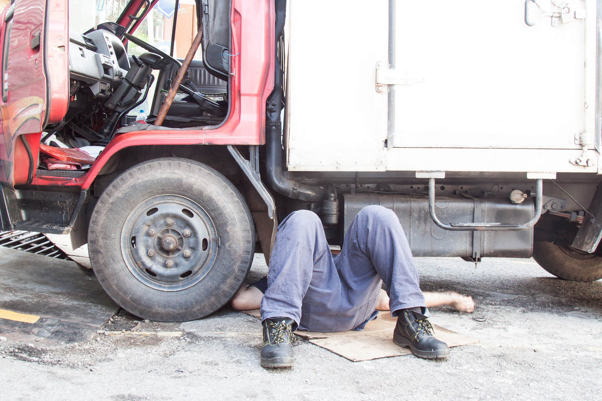 mechanic laying on the ground working under a box truck