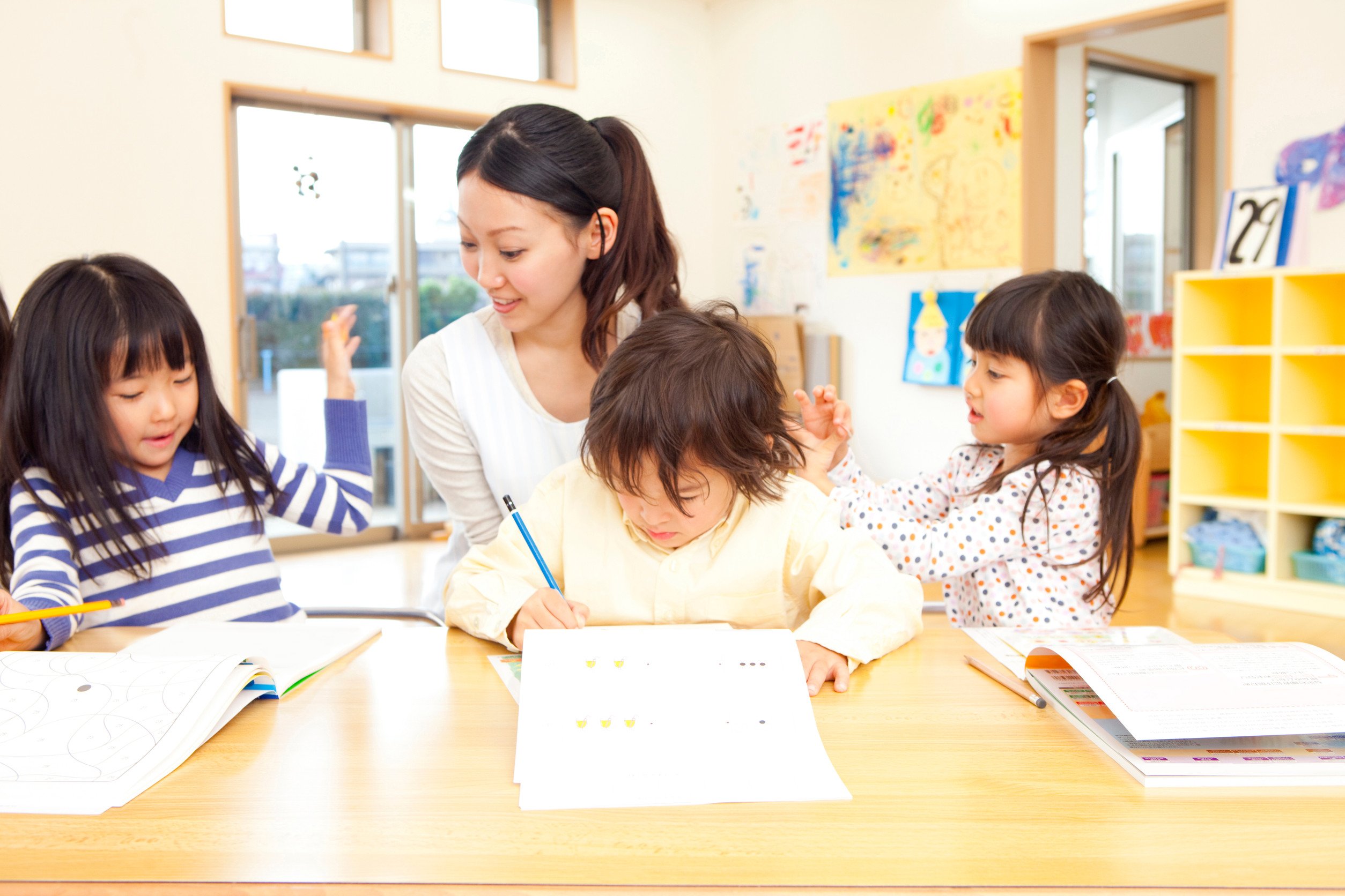 three children at a learning center being instructed by a teacher