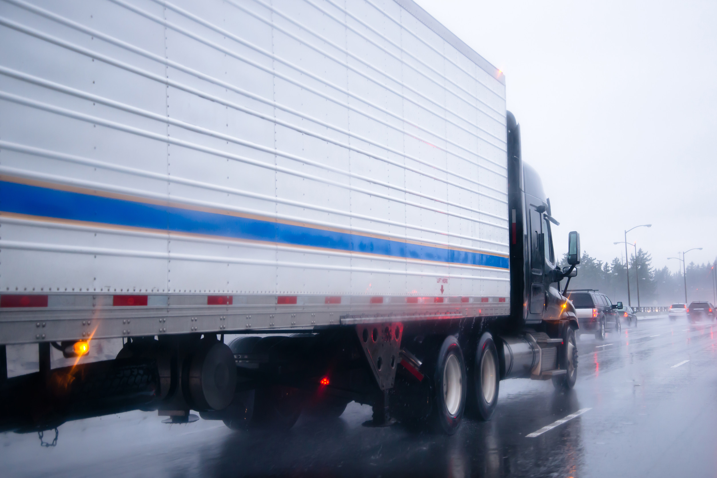a tractor trailer drives down a rainy highway