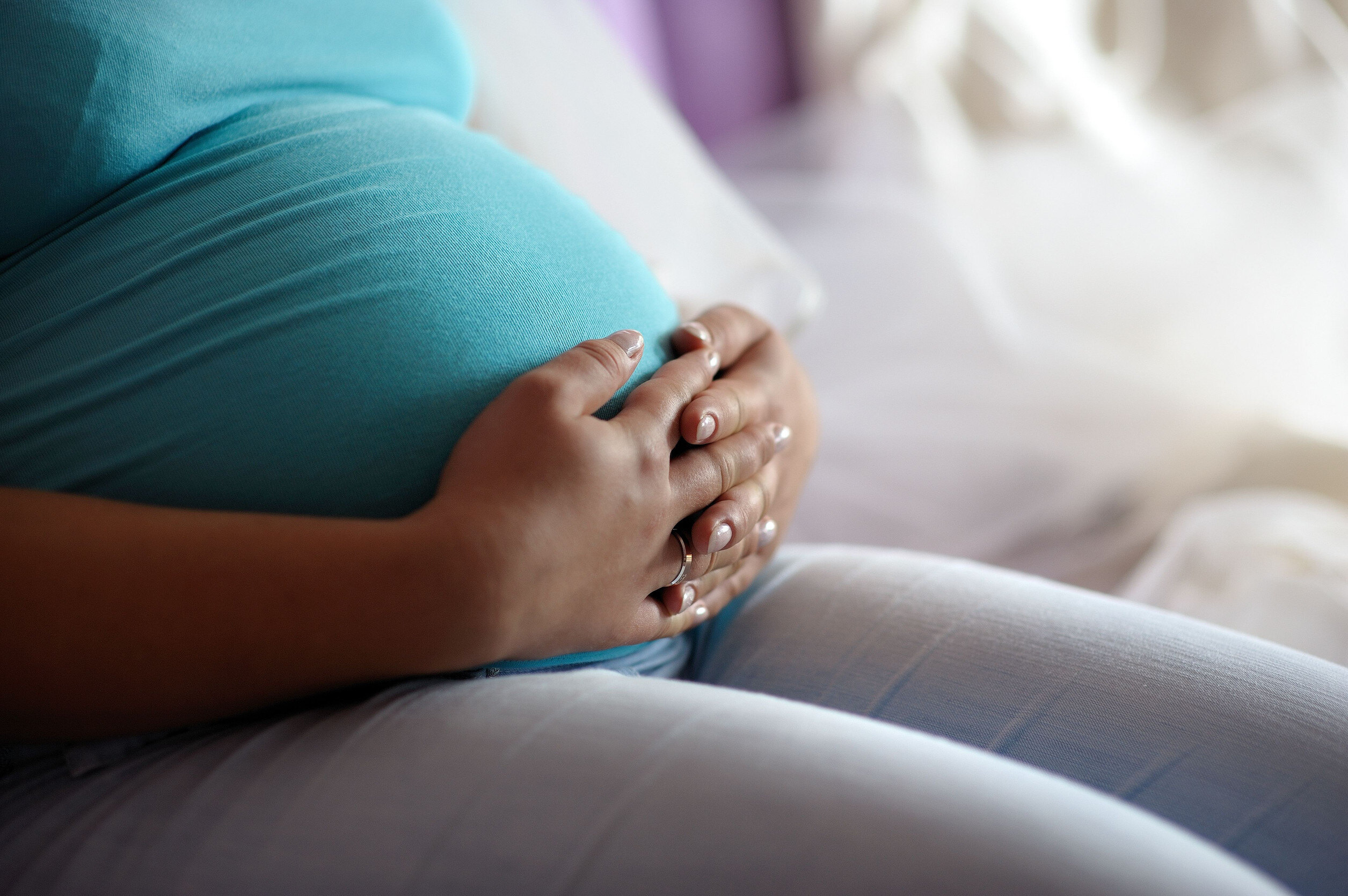 a pregnant woman clasps both hands around her belly
