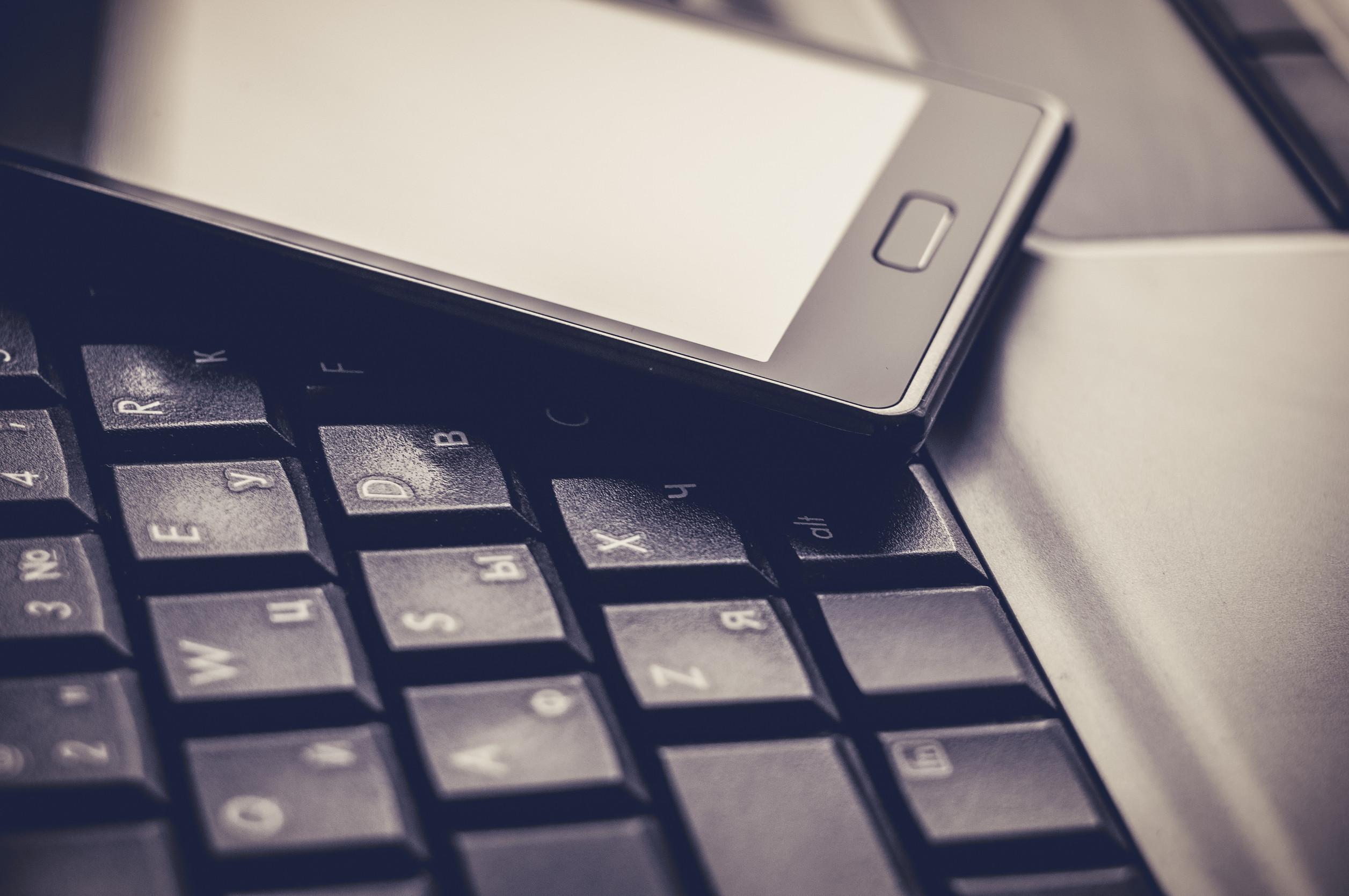 closeup of a smartphone resting of a laptop keyboard