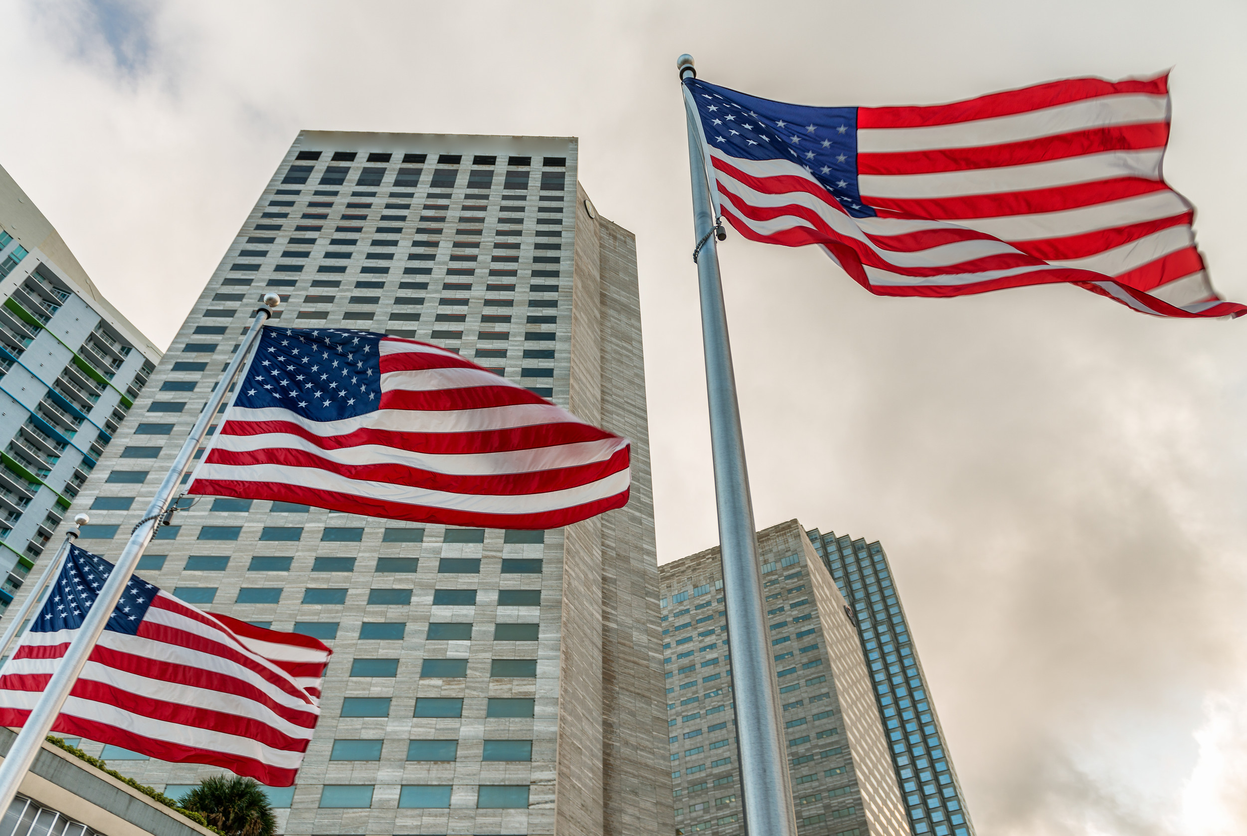 three american flags on flag poles outside of an official high rise