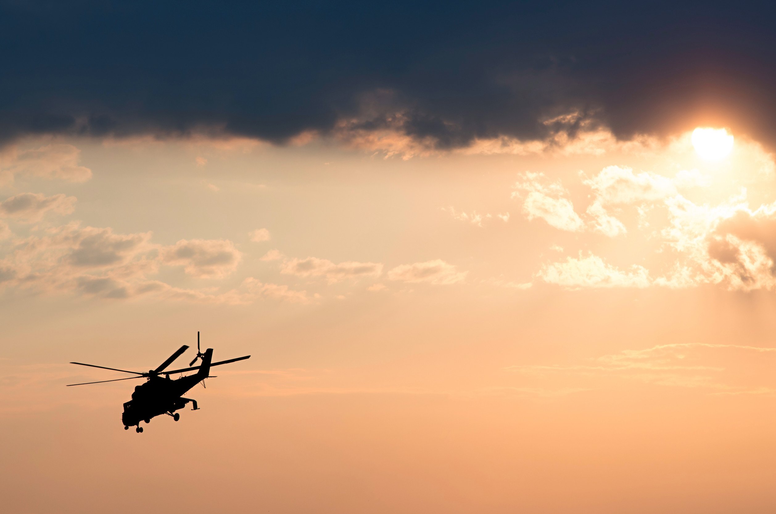 silhouette of a military helicopter against a sunset sky