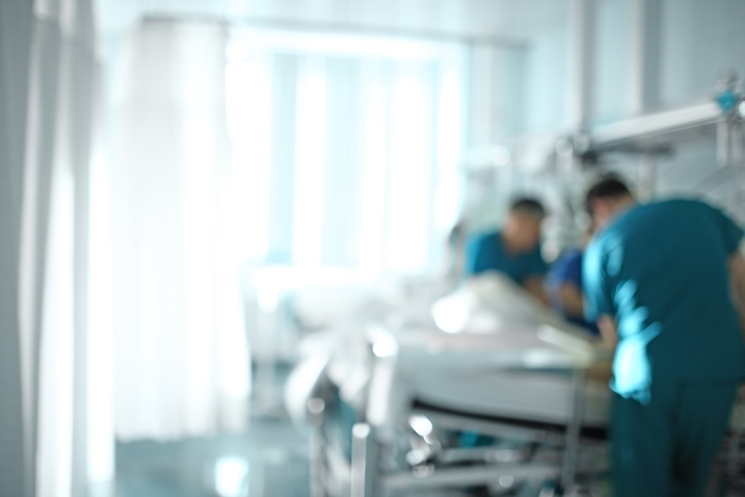 Medical doctor team at the bedside of patient, unfocused background