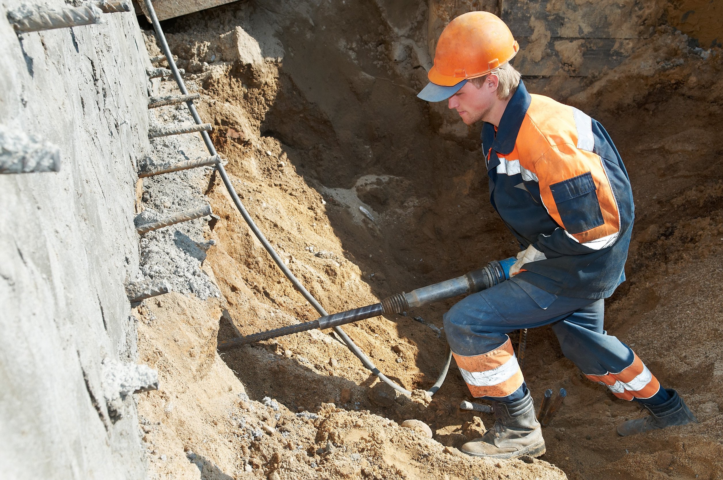 young builder at construction site working with pneumatic plugger hammer