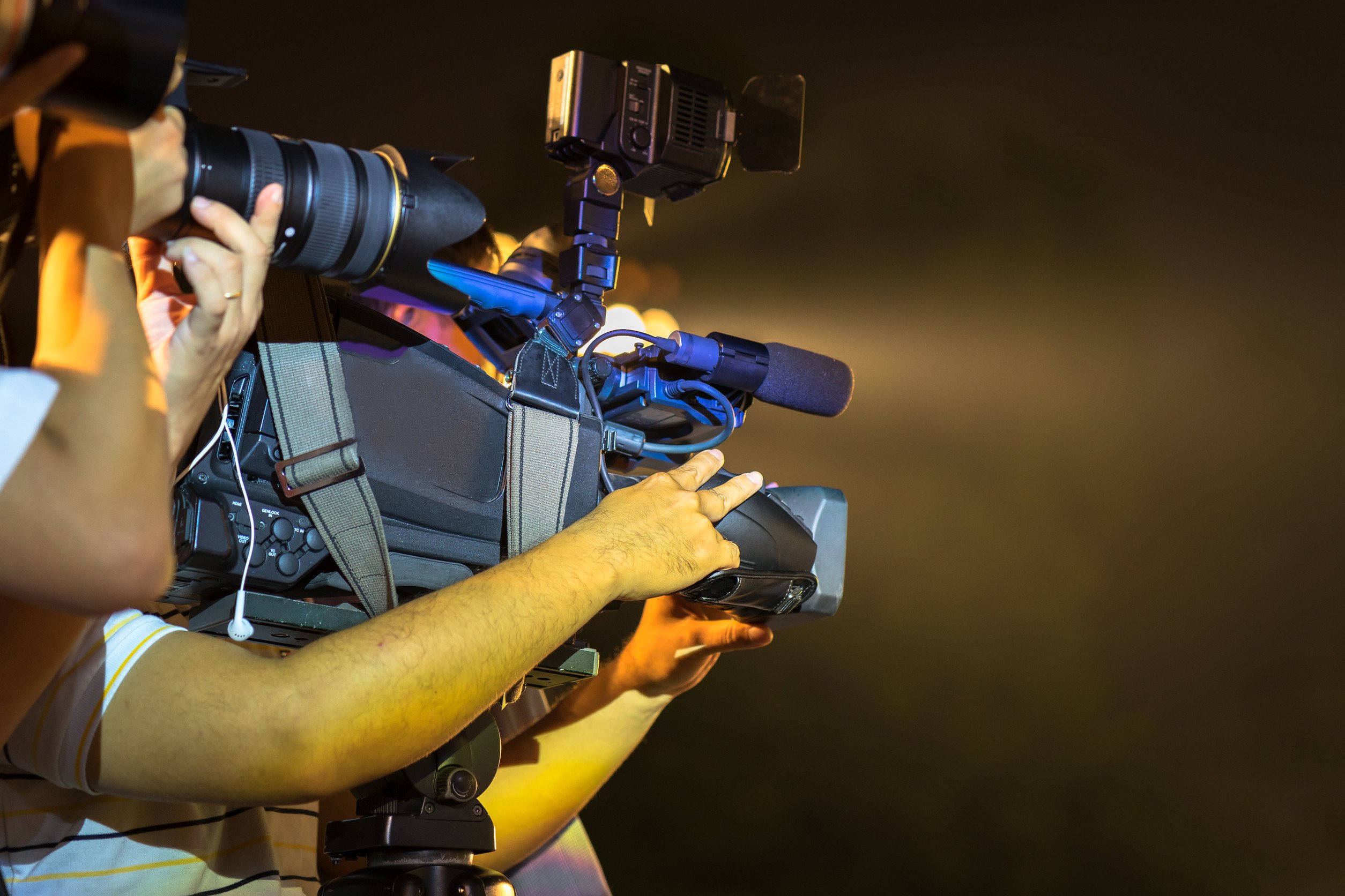 Closeup of professional television camera operator in event at night