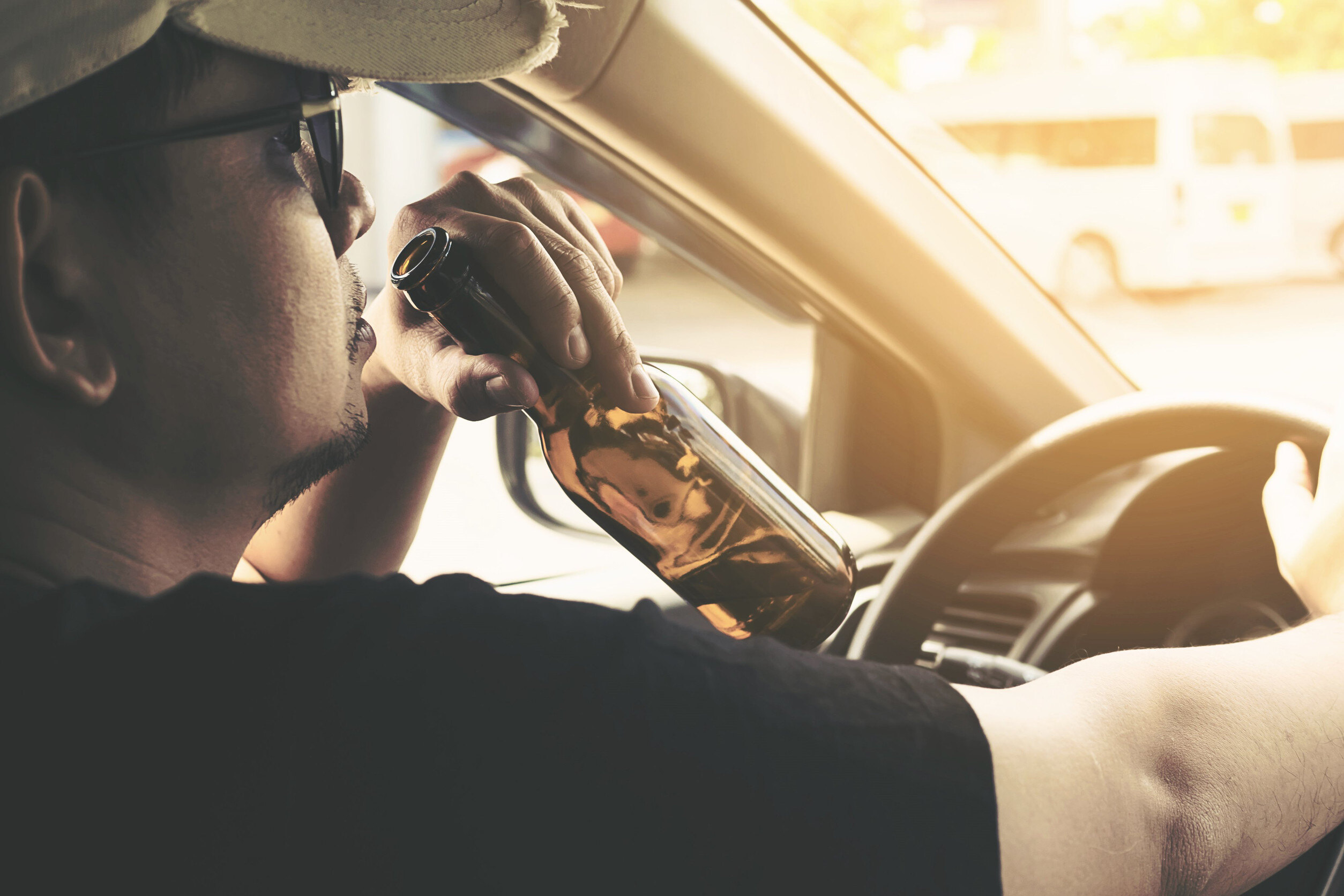 a man drinking from a bottle while driving