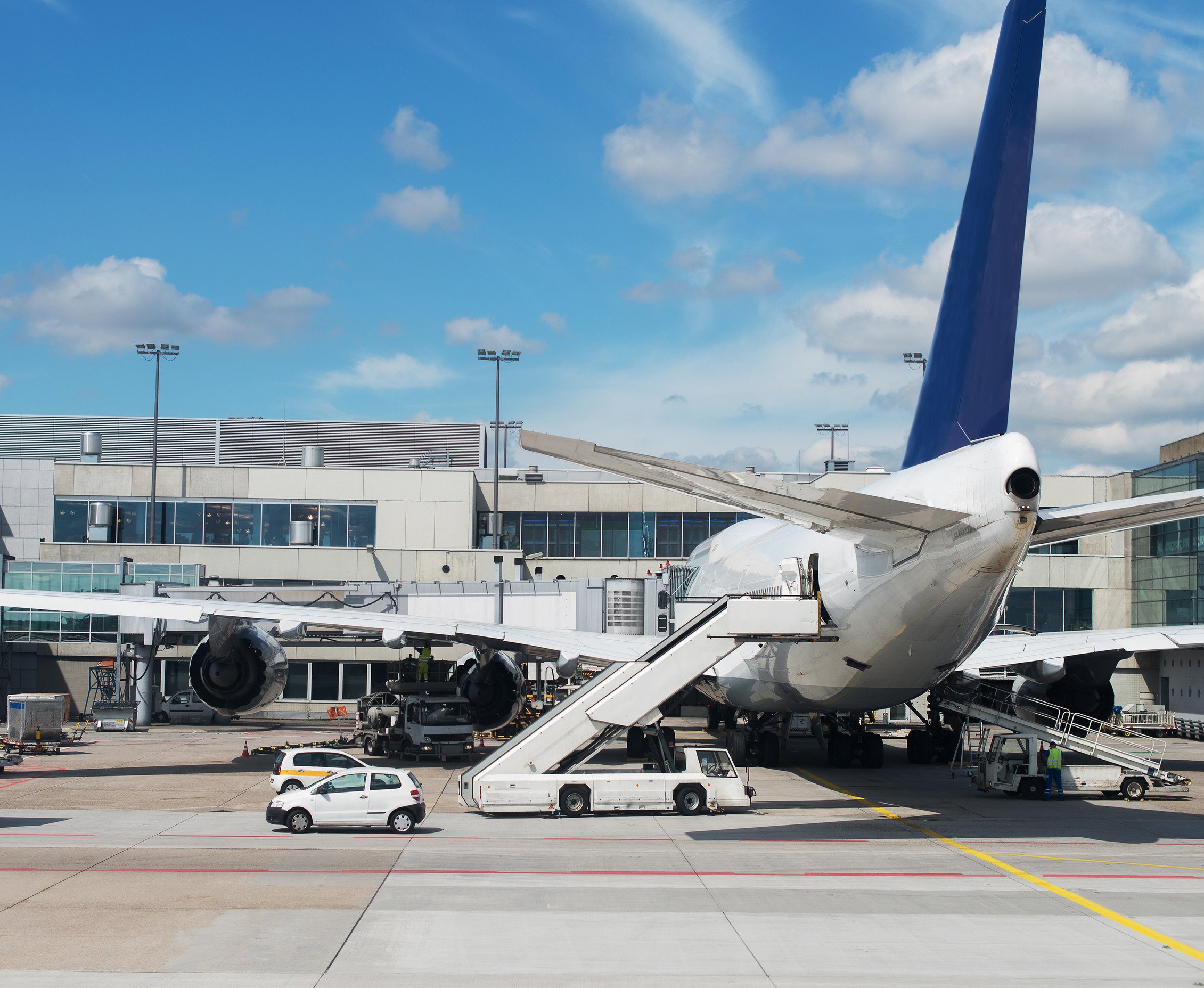 a passenger aircraft docked at an airport and being serviced by a ground vehicle