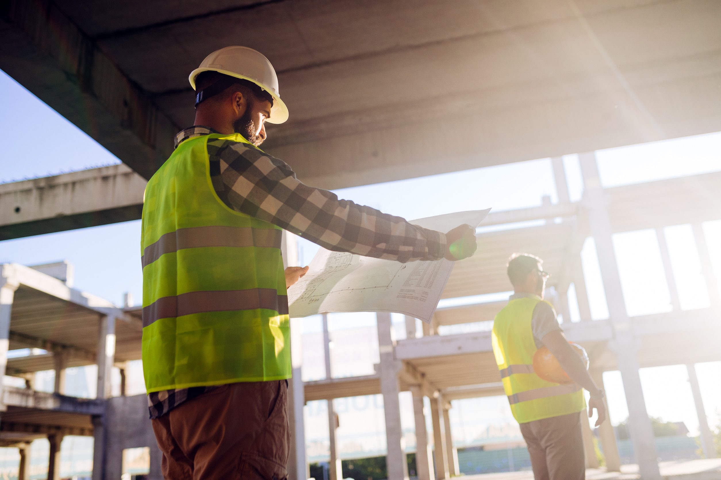 construction worker in high visability safety gear examining a building schematic