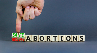 Finger touching wooden blocks that can either spell safe or unsafe abortions.