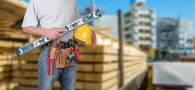 Worker with a tool belt and a helmet on a construction site.