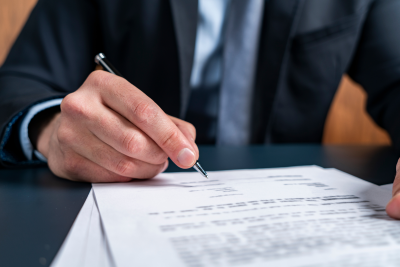 closeup of a suited person's hand signing a contract