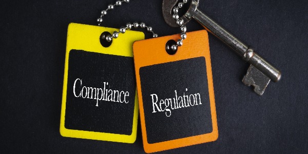 compliance-regulation-inscription-written-on-wooden-tag-and-key-on-black-background