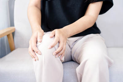 Person suffering from knee pain sitting on sofa