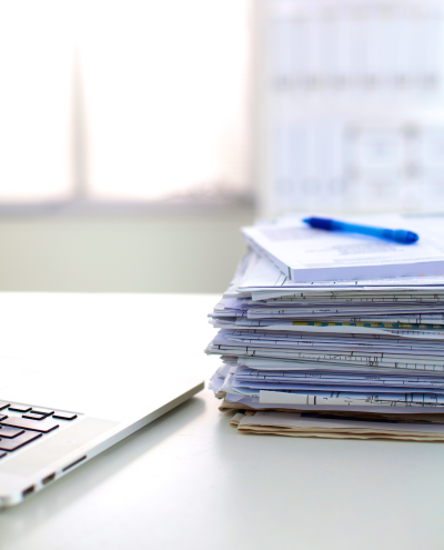 Stack of papers next to a laptop