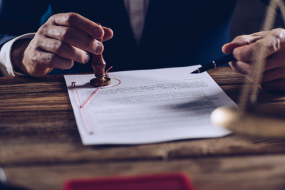 legal document on wooden table being stamped by person in a business suit