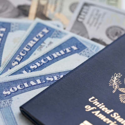 united states passport laying atop a stack of social security cards and american paper money