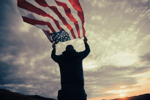 Man standing outside holding U.S. Flag over head