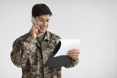 Veteran on the phone while looking at papers on a clipboard.