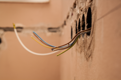 exposed wiring protruding from circular holes in a plaster wall