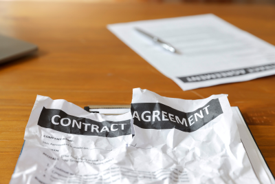 A crumpled contract agreement on a wooden desk