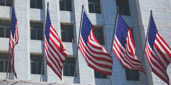 view of waving American flag in the wind with beautiful blue sky in background